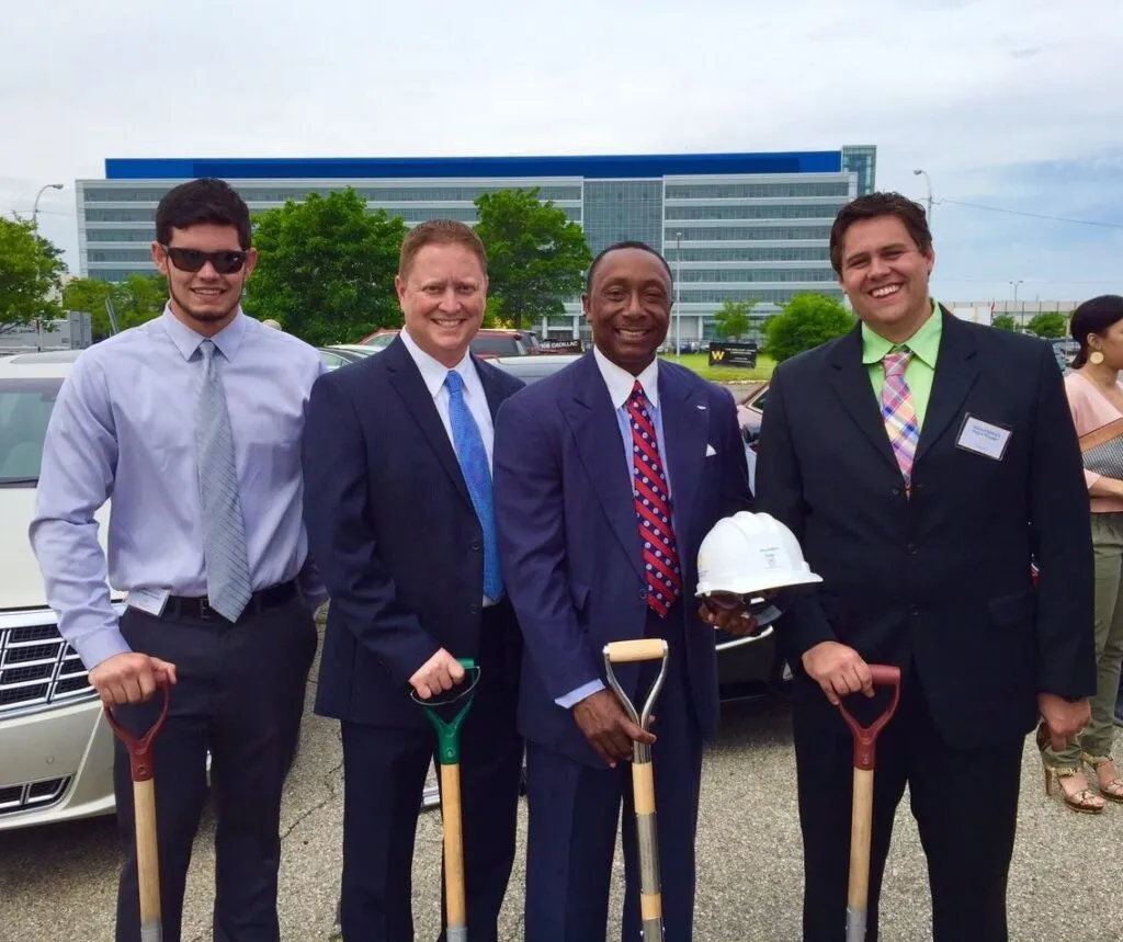 Four men in suits hold shovels for groundbreaking ceremony