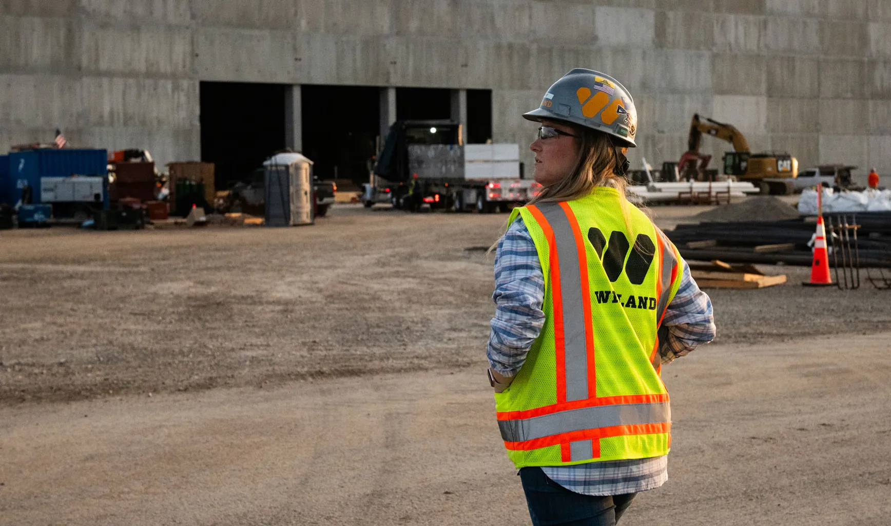 A woman stands in front of a construction site