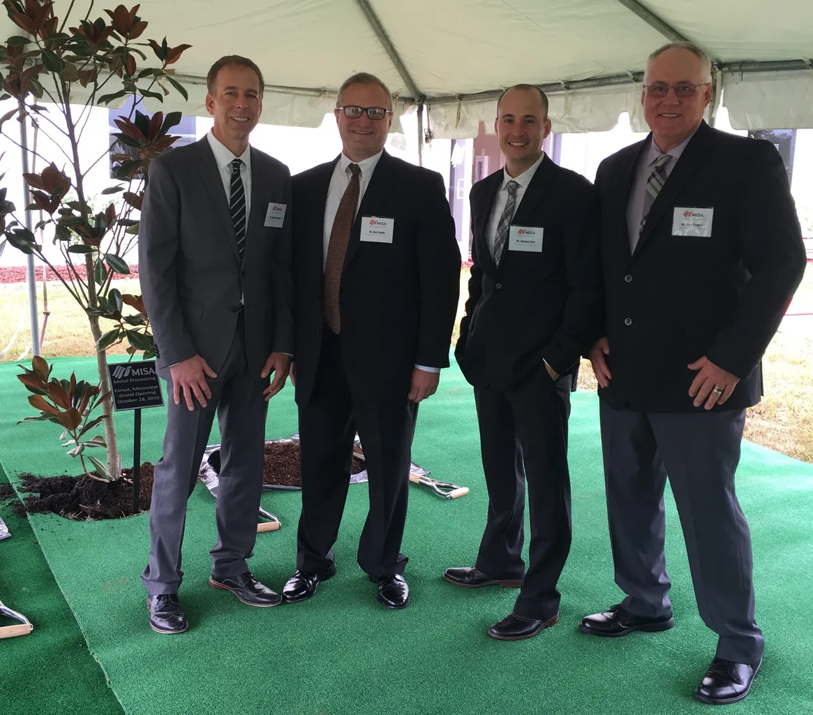 Four men in suits stand under a tent