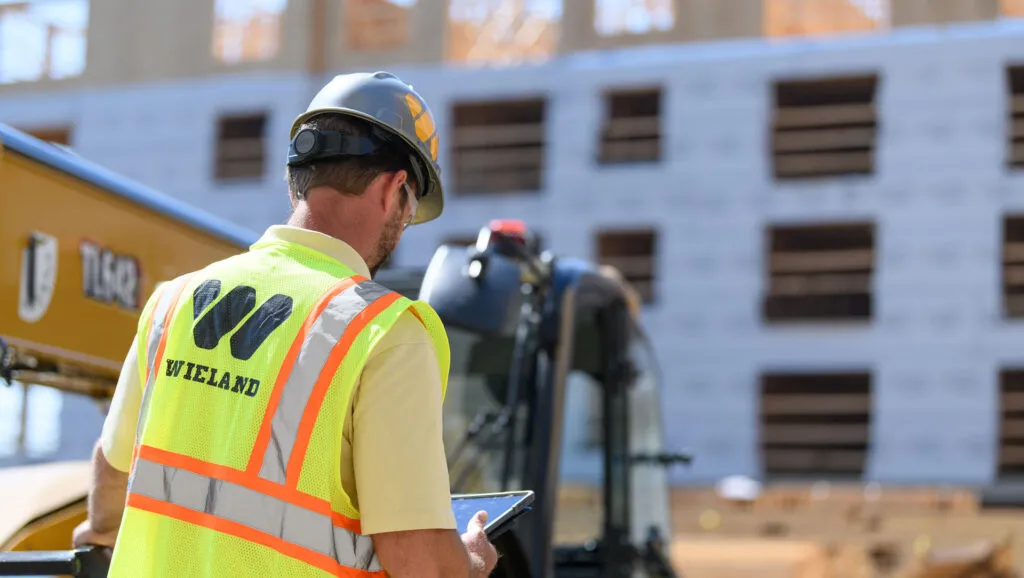 A man looks down at a tablet at a construction site