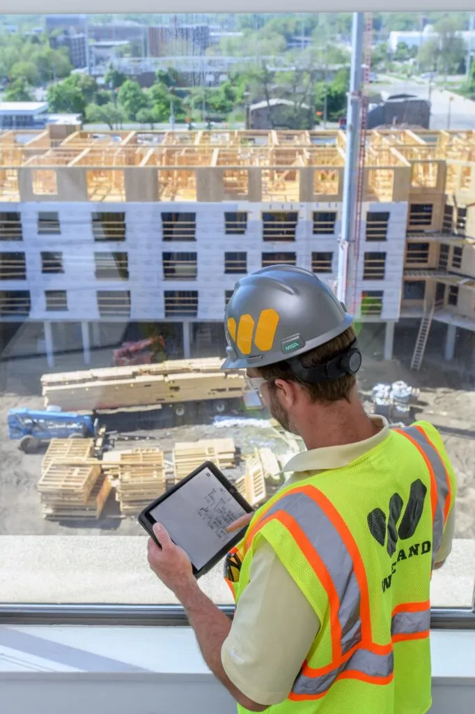 WIELAND team member reviews plans while standing above a worksite.