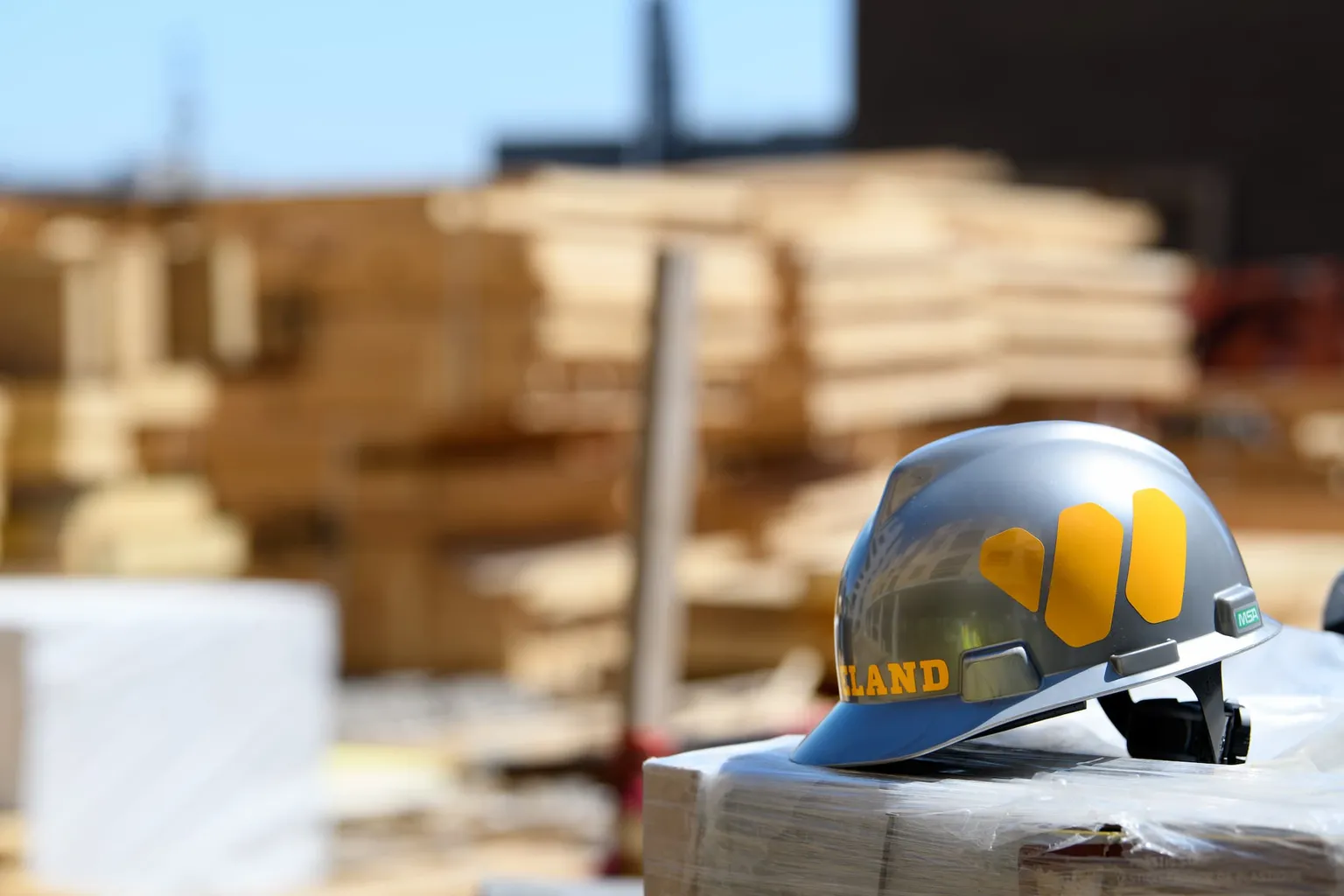 Close up of a WIELAND branded safety helmet with build site materials stacked in the backdrop.