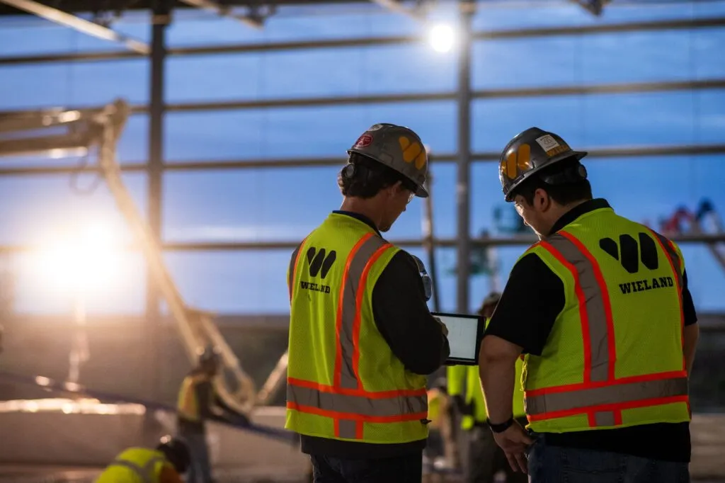 Two WIELAND team members discuss plans at a worksite