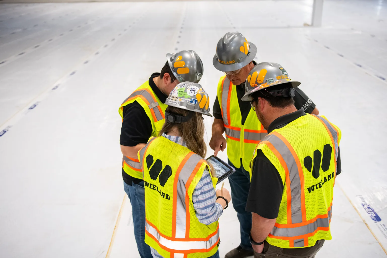 Group of four WIELAND team members in safety gear have a close discussion on site.