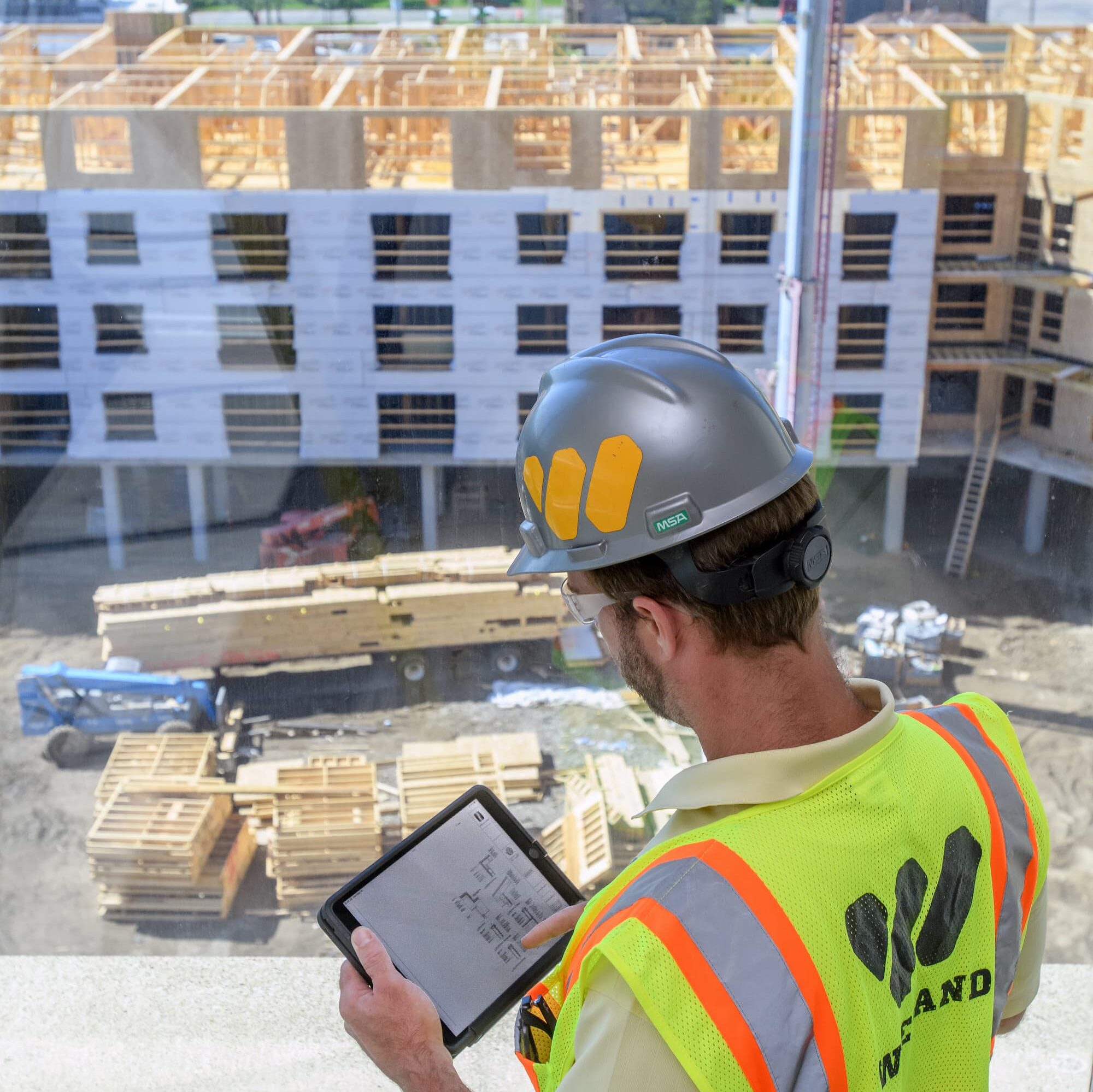 Employee reviews on a tablet while looking at a jobsite below