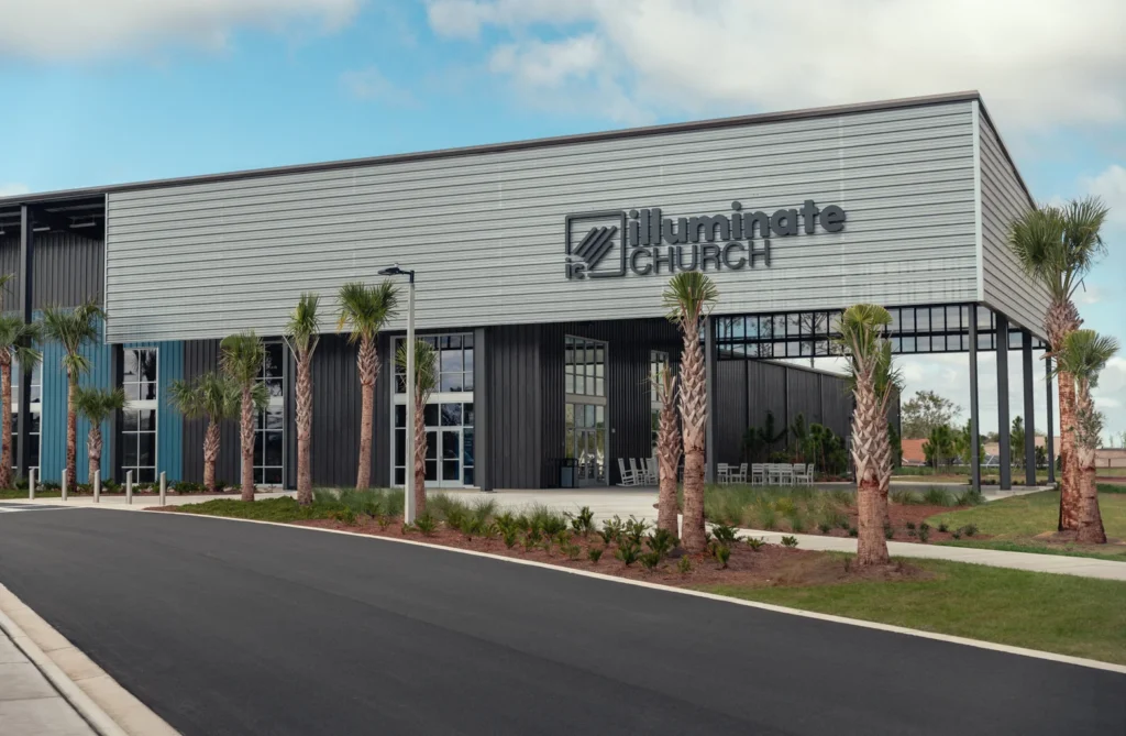 Front view of Illuminate Church in Celebration, FL, featuring palm trees and a grassy area.