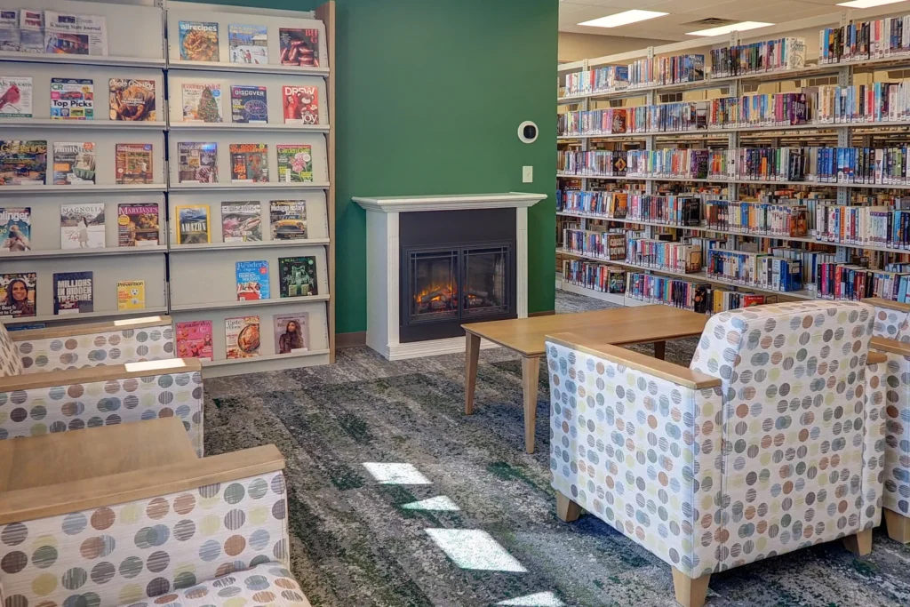 Interior of Briggs District Library in St. Johns, MI, showcasing comfortable chairs and a fireplace for a welcoming space.