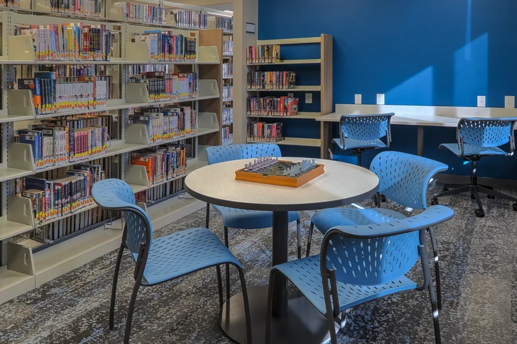 Briggs District Library in St. Johns, MI, displaying blue chairs and tables in a welcoming reading environment.