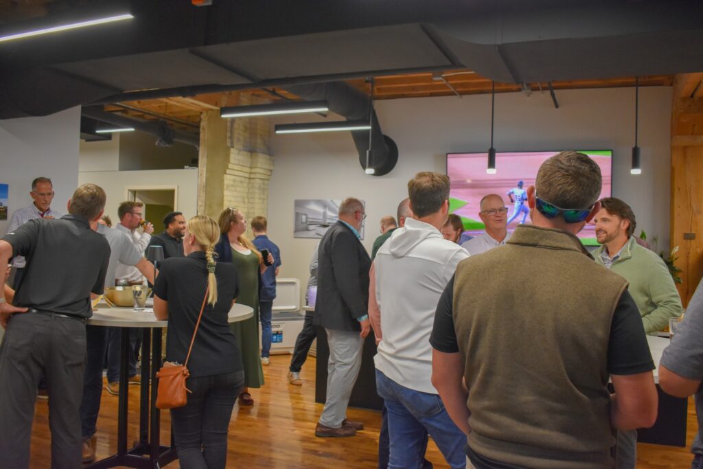 Group gathered in a new office space watching a baseball game.