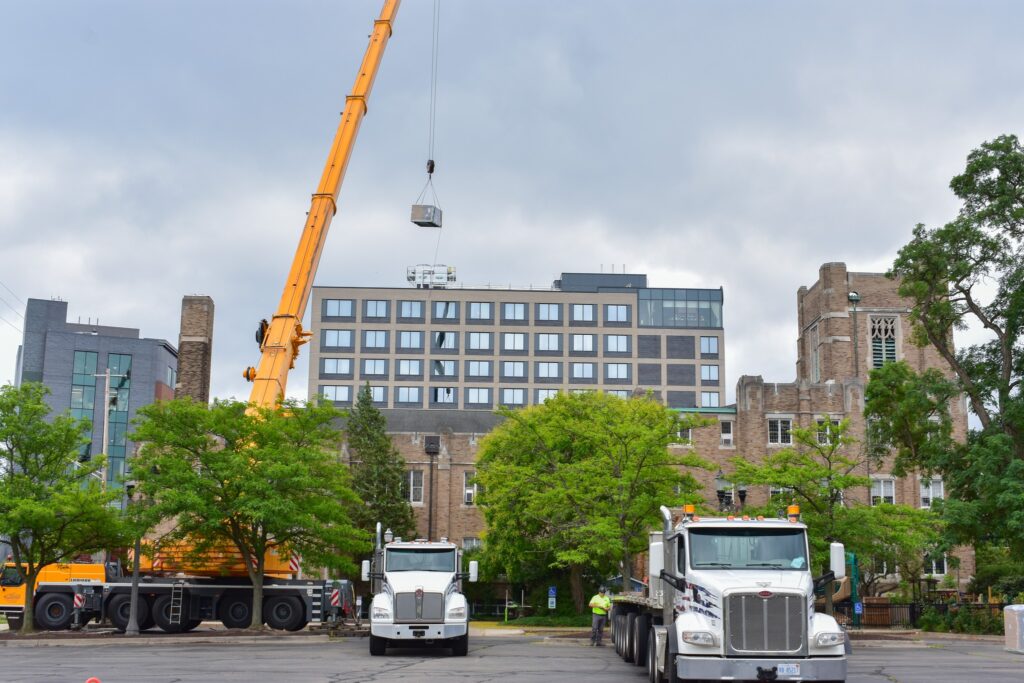 Crain lifting an AC unit to the roof section of a church building.