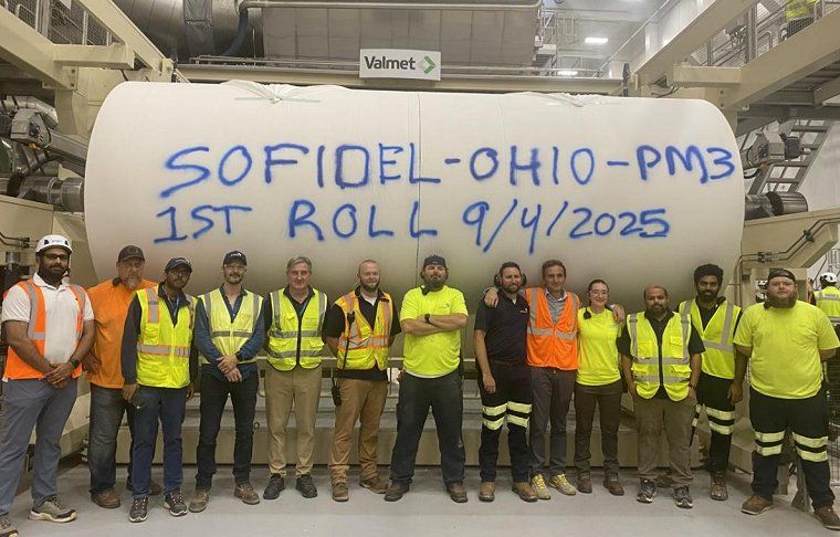 Employees gathered in front of a large paper roll. The paper roll was the first produced at Sofidel's new Circleville location.