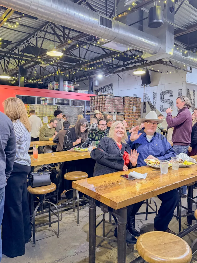 Group waving to the camera as they enjoy a meal at Lansing Brewing Company