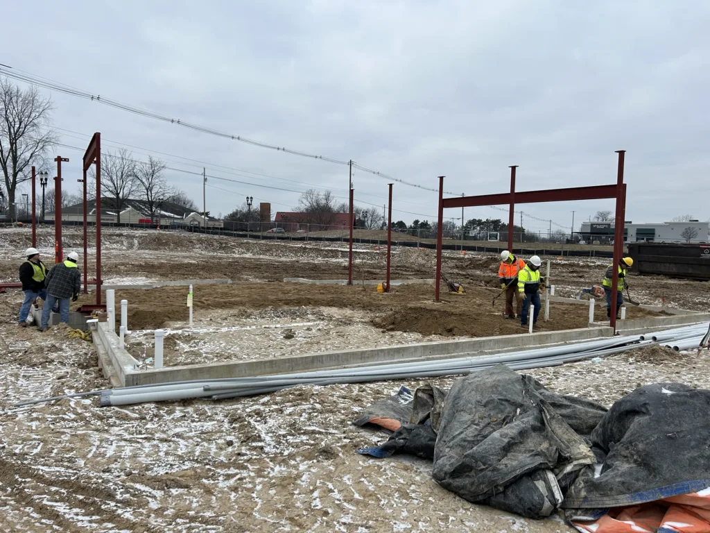 Two men working on earthwork outside the future facility