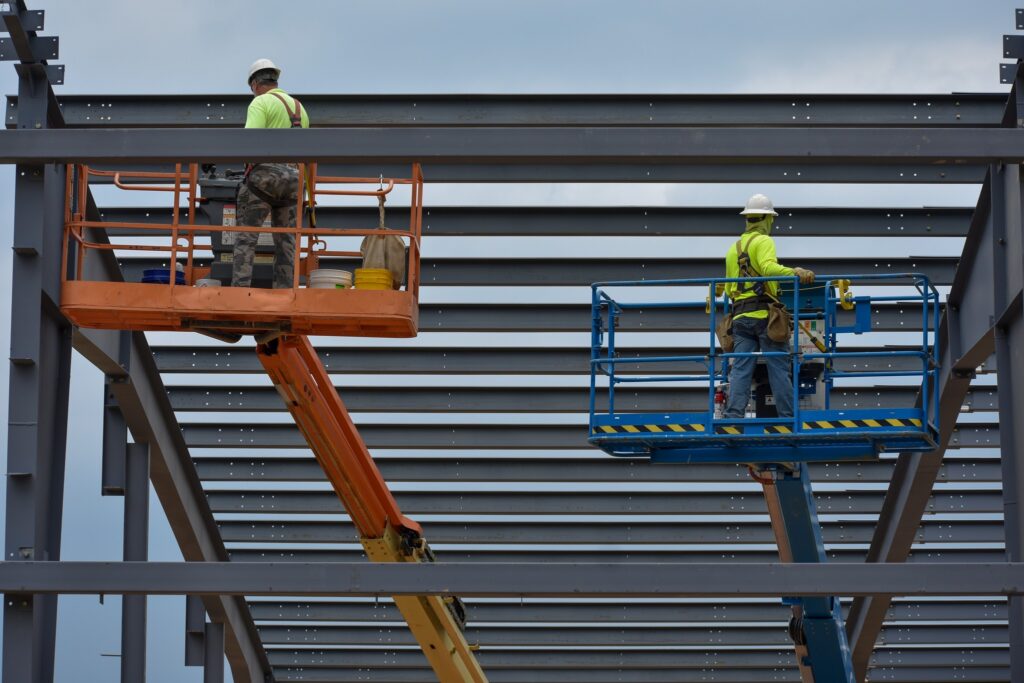 Two men in boom lifts help with the steel erection on site.
