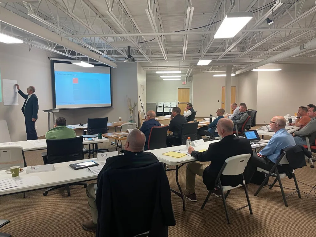Group gathered and listening to a presentation draw on a white board