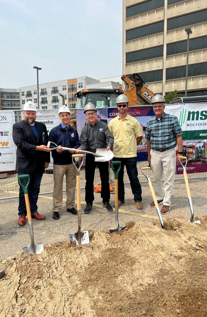 Group gathered holding shovels and wearing hardhats at the Groundbreak ceremony of The Ovation