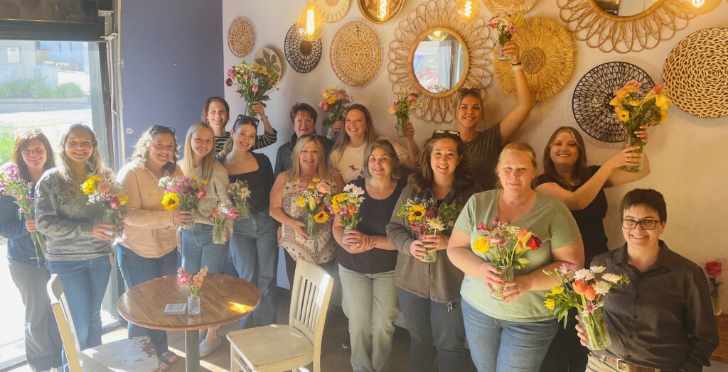 Group of women gathered and smiling with their bouquets of flowers