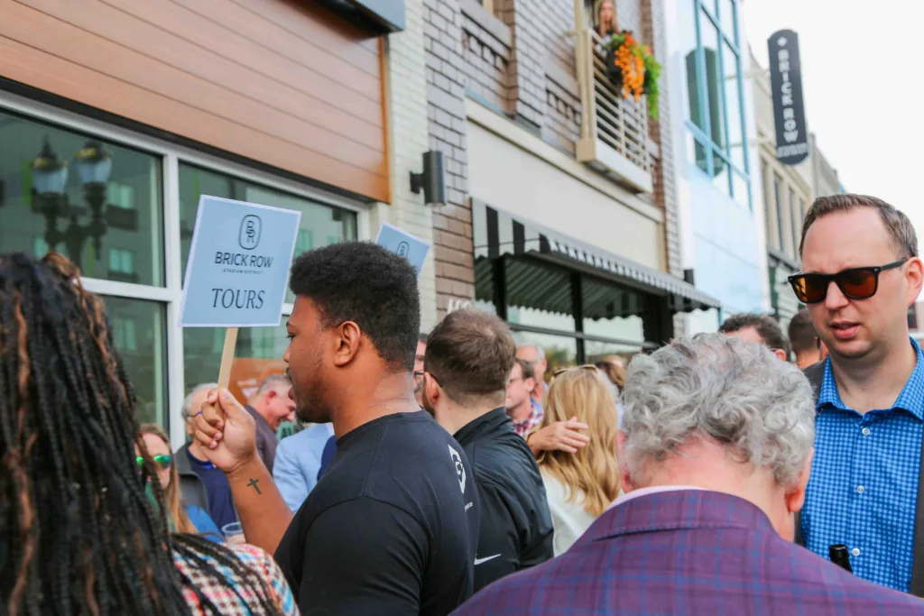 The busy crowd showing up for the grand opening ceremony. Gillespie Group employees hold "Tours" signs to encourage attendees to view the building. 